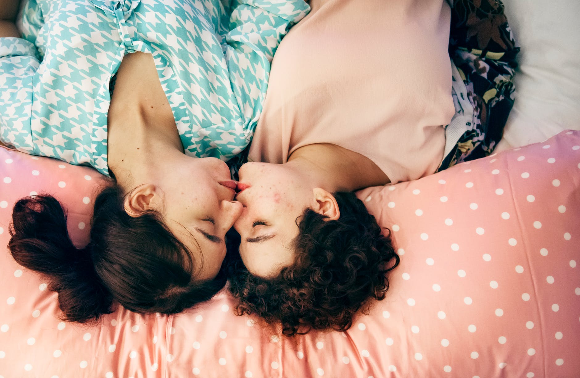 two woman kissing on bed